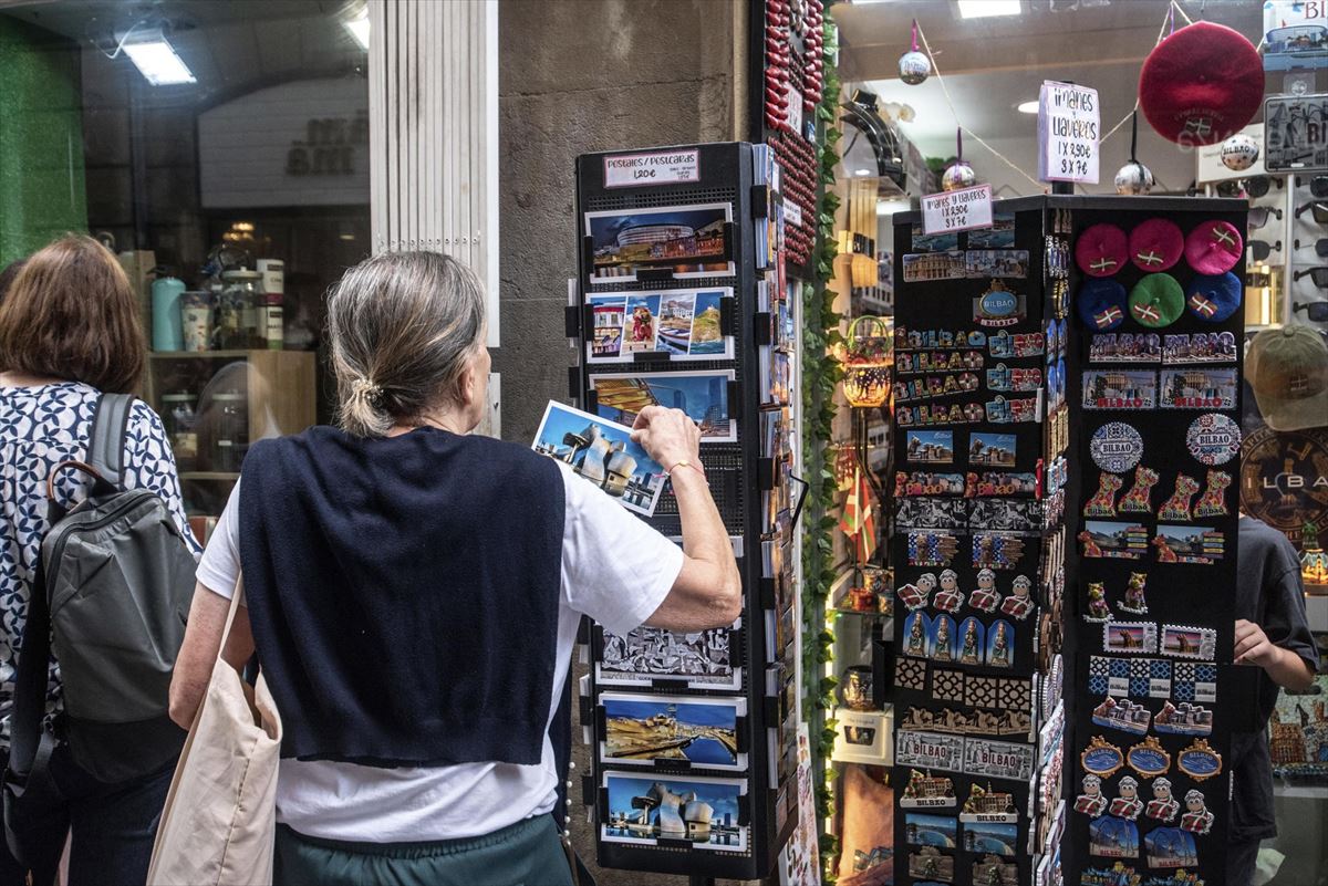 Una turista ojea una postal en Bilbao